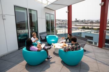 students studying on a balcony with round blue chairs