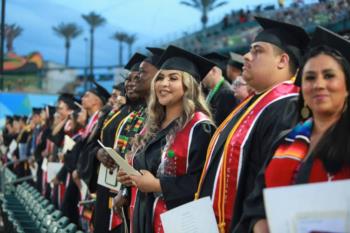 graduates in caps and gowns standing in a stadium