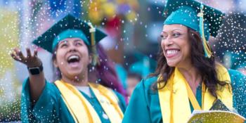 graduates in green gowns celebrating with confetti
