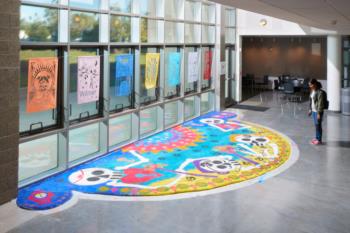 Sand art mural on the floor in front of windows at University of Redlands art building