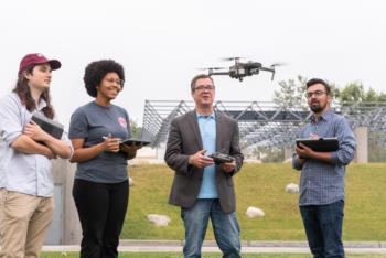 Three students and professor using drone