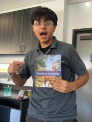 student holding a brochure with 'woodbury university' on the cover