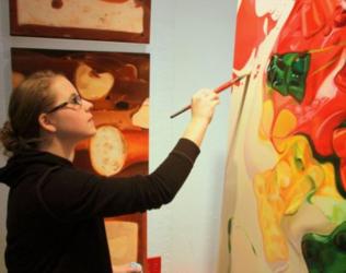 student painting on a large canvas in an art studio