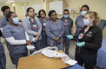 Nursing students observe professors instructions