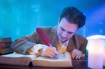 actor in costume writing with a feather quill