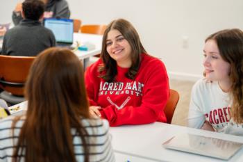 students in sacred heart university apparel smiling in a classroom