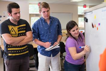 three students collaborating with whiteboard
