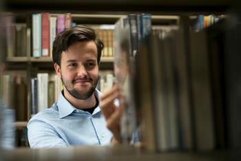 man searching for books in a library
