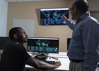 two people discussing over a computer with screen graphics