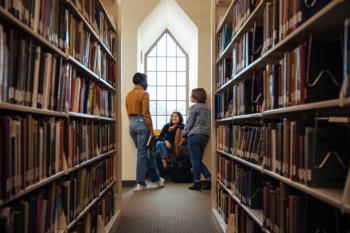 students chatting in a library aisle
