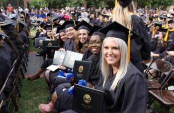 graduates in caps holding diplomas smiling at ceremony