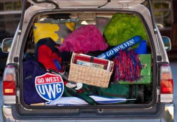 car trunk packed with items and 'GO WEST UWG' sign