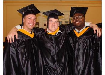 three graduates in caps and gowns smiling
