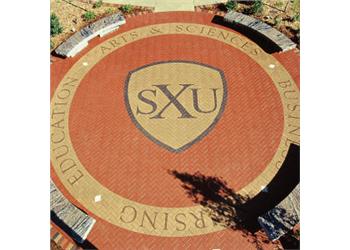 brick pavement with 'SXU' shield logo and text 'education arts &amp; sciences business'