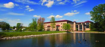 campus building by the lake with ducks and clear sky
