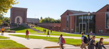 students walking on campus pathways with buildings