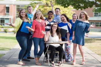 group of students smiling and posing outside on campus