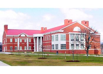 red-brick campus building with large windows and young trees