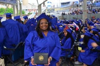 graduate in blue cap and gown holding diploma at ceremony