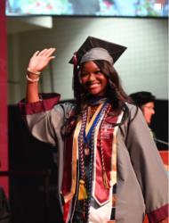 graduate in cap and gown waving during ceremony