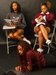 three students reading and studying with a laptop in a classroom setting