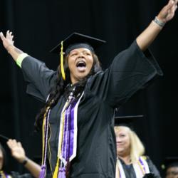 graduate cheering in cap and gown