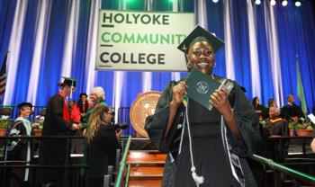 graduate smiling with diploma at holyoke community college ceremony