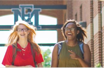 two students happily walking on campus with emcc sign in background