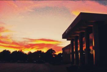 sunset behind a building with glowing windows