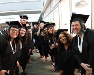graduates in caps and gowns smiling in a hallway