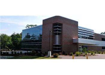 brick and glass building with landscaped lawn