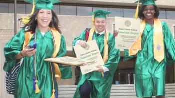 graduates in green gowns holding essex county college diplomas