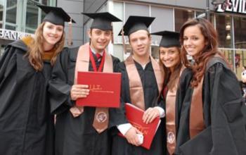 graduates in regalia holding diplomas