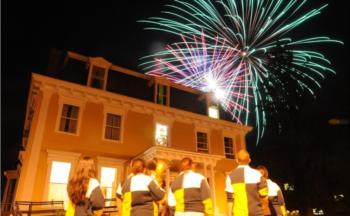 people watching fireworks near a building at night