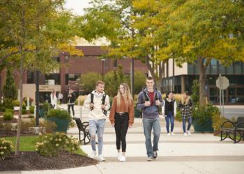 students walking on a tree-lined pathway at the campus