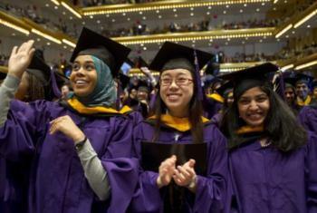 graduates in purple robes waving and smiling at ceremony