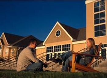 two students relaxing outside with campus buildings