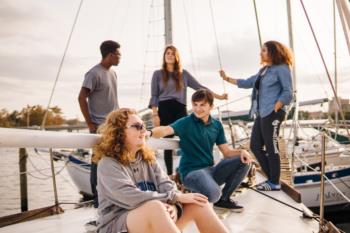 students talking on the dock near sailboats