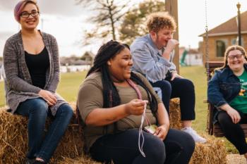 students sitting on hay laughing together