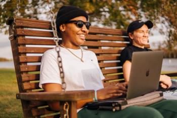 two students on a bench with a laptop