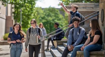 students gather on steps outside, enjoying a sunny day on campus