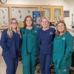 four students in medical scrubs standing in a healthcare setting