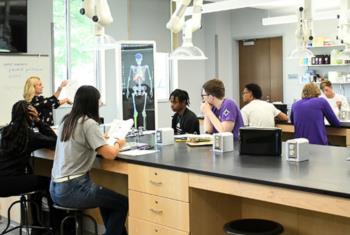 students in a science classroom with anatomical poster