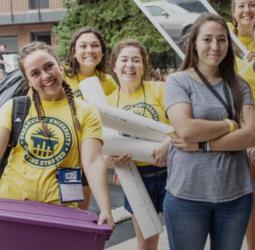 students in yellow 'cedarville university ring starter' shirts holding move-in supplies