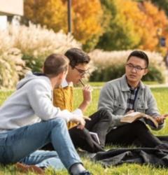students sitting on grass having a discussion on campus