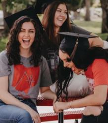 three graduates laughing wearing ccad shirts and caps