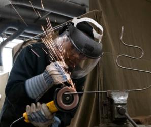 student using a grinder with sparks flying in an art workshop