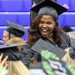 graduate in cap and gown smiling at commencement