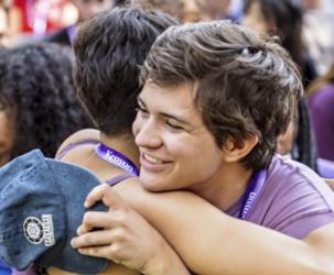 students embracing at a campus event, one wearing a kenyon lanyard