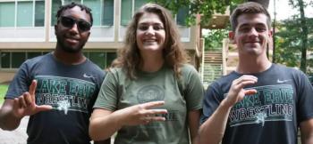three students smiling wearing lake erie wrestling shirts